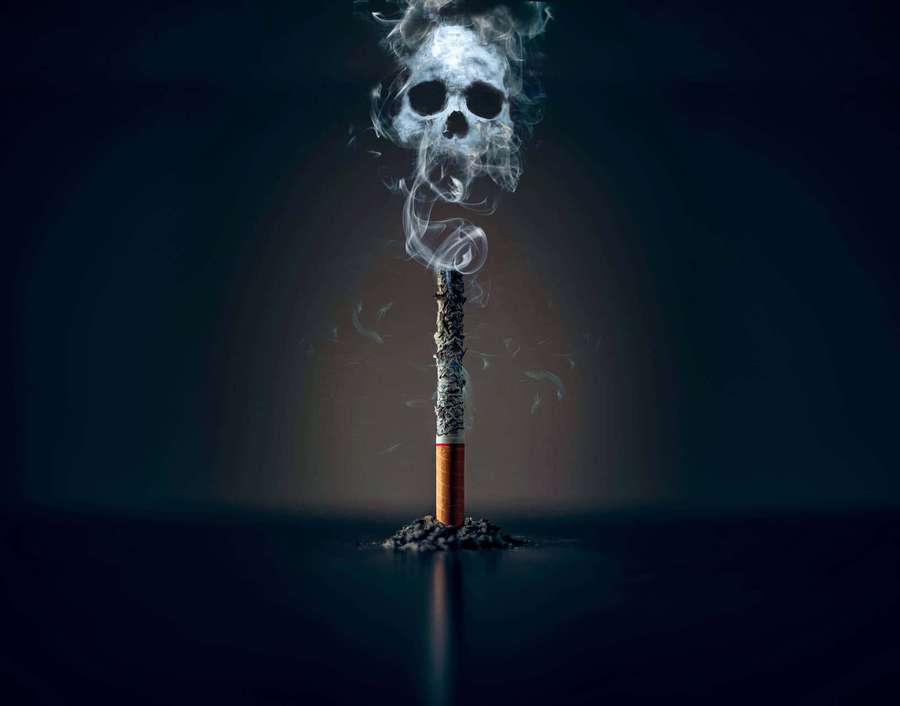 A cigarette emitting smoke shaped like a skull against a dark background. — Cigarette Picture