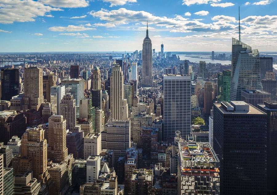 Vista panorâmica do horizonte de Nova York com o Empire State Building e arranha-céus ao redor sob céu ensolarado. — Cityscape Papéis de Parede