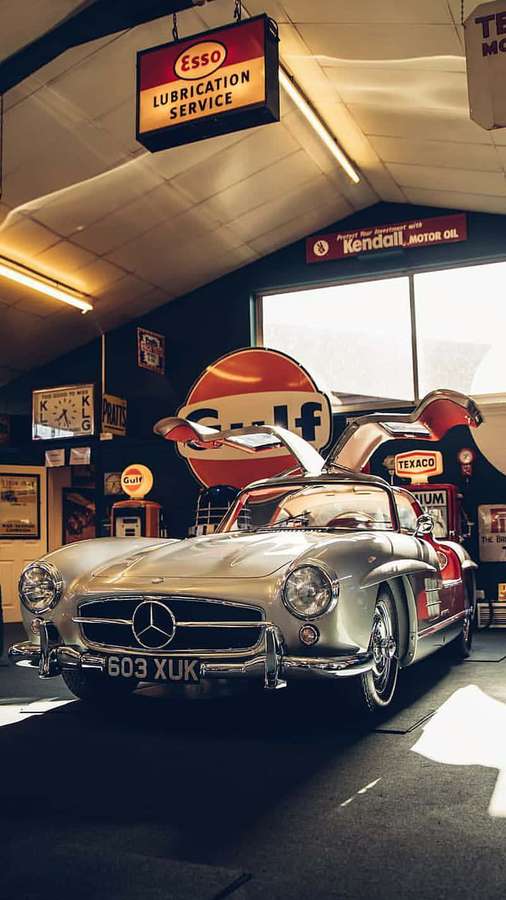 Silver Mercedes-Benz 300SL Gullwing in vintage gas station garage with classic signs. — Classic Mercedes Wallpaper
