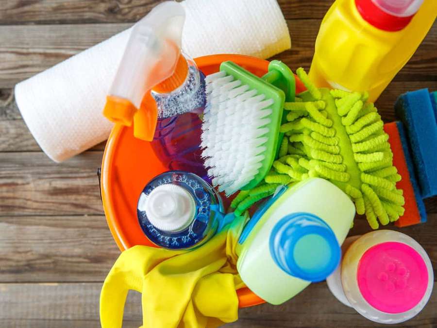 A colorful collection of cleaning tools and products on a wooden floor. — Cleaning Wallpaper
