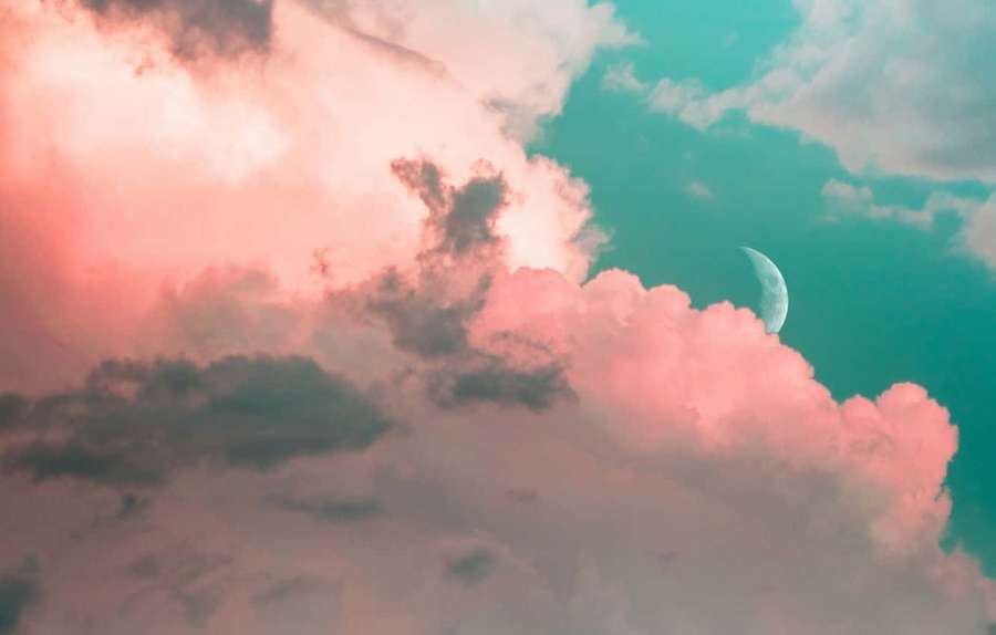 Crescent moon glowing behind pink and teal clouds at twilight. — Clouds Background