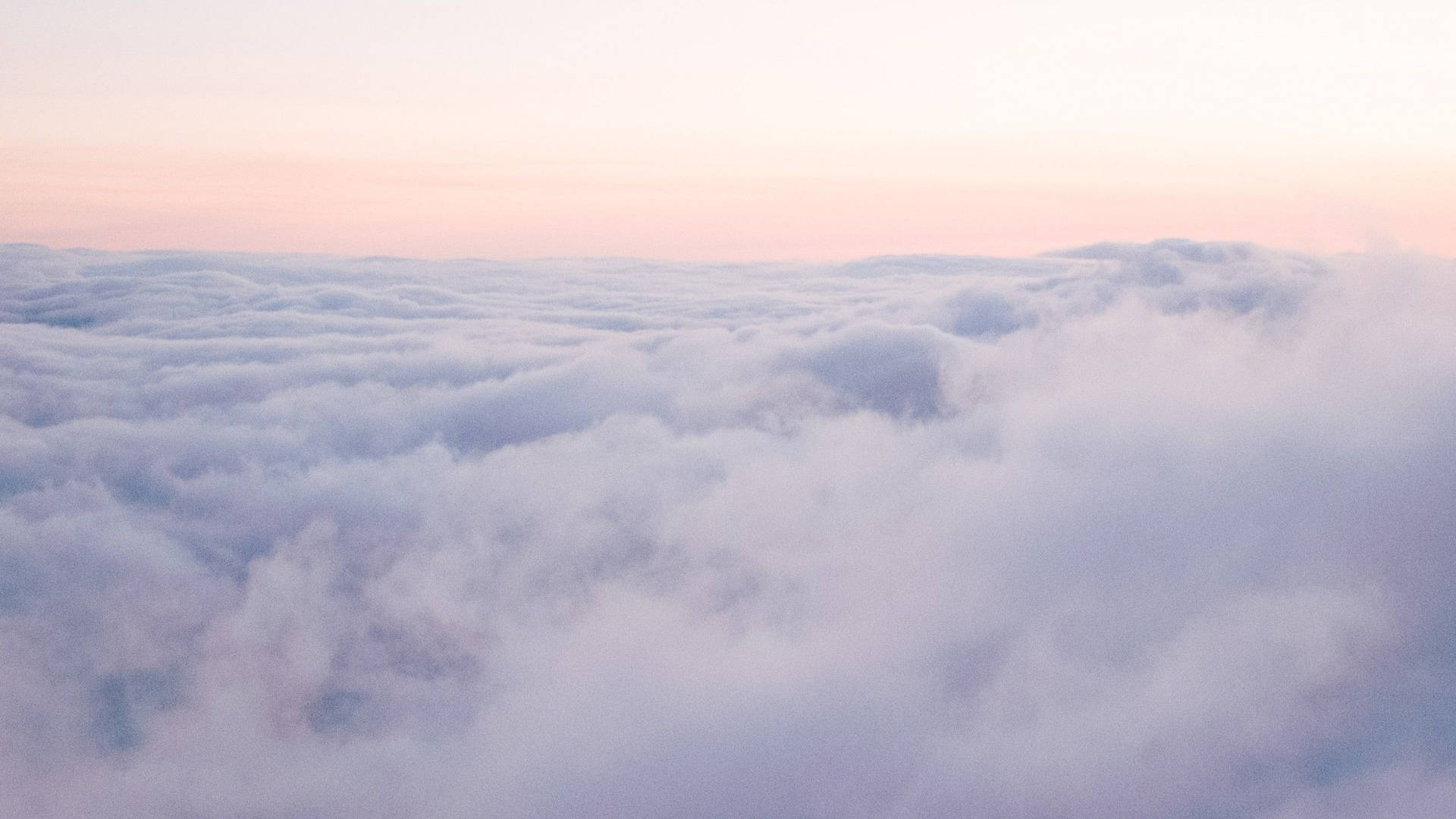 Soft pink and lavender clouds stretch endlessly under a gentle dawn sky. — Cloudy Wallpaper