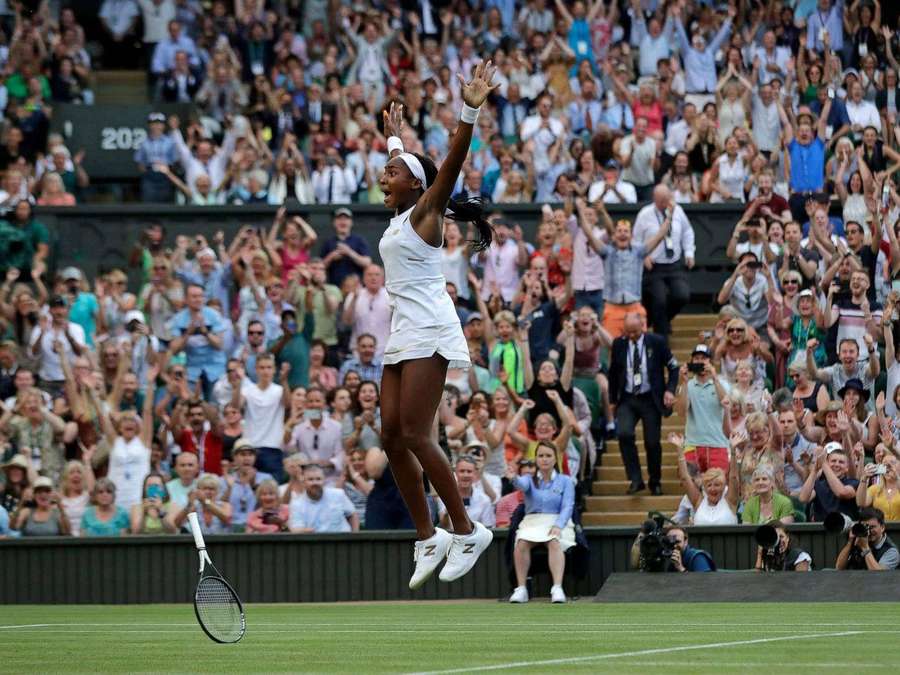 Tennisspielerin feiert Sieg mit erhobenen Armen auf dem Rasenplatz. — Coco Gauff Hintergrundbild