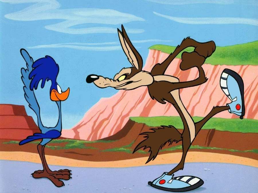 Wile E. Coyote equilibra-se em um pé enfrentando um roadrunner azul em um desfiladeiro do deserto. — Coiote Papéis de Parede