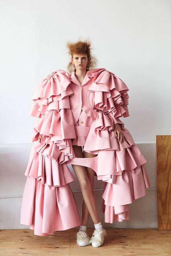 Modelo em look rosa volumoso com babados posando em estúdio com piso de madeira. — Comme Des Garçons Papéis de Parede