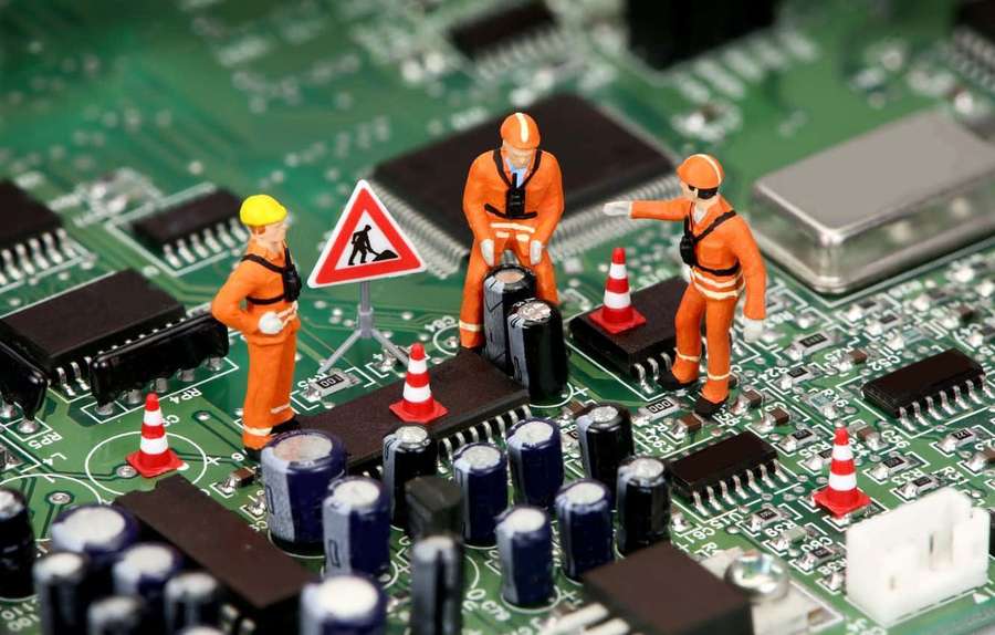 Equipo de construcción en miniatura trabajando en una placa de circuito con conos de tráfico y señales de advertencia. — Componentes Electrónicos Fondos de pantalla