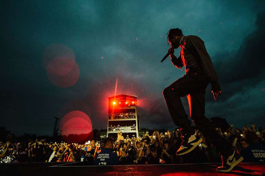 Rapper se apresentando no palco à noite com multidão torcendo sob luzes vermelhas. — Concerto de Travis Scott Papéis de Parede