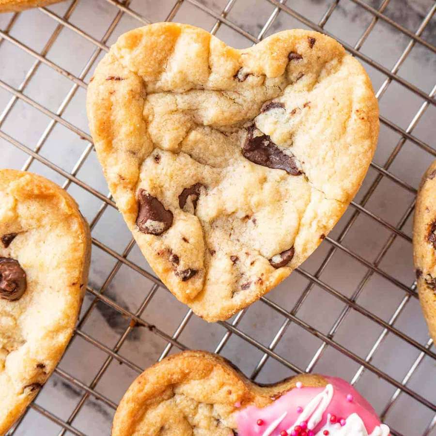 Herzförmige Schokoladenkekse kühlen auf einem Gitterrost, einer mit rosa und weißem Zuckerguss. — Cookie Bilder
