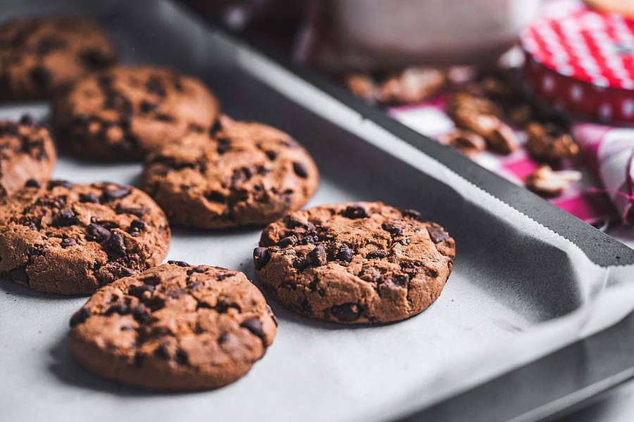 Galletas de chispas de chocolate recién horneadas en una bandeja para hornear con nueces y un paño a cuadros rojos. — Cookie Fondos de pantalla
