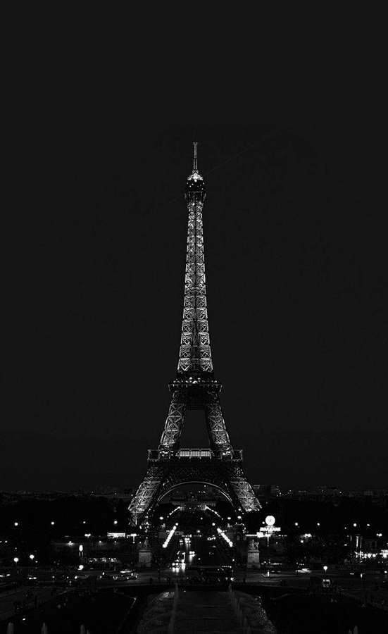 Eiffel Tower lit up at night against a dark sky with city lights below. — Cool Black Wallpaper