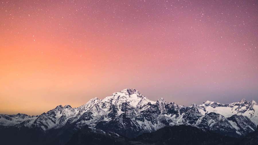 Snowy mountain range under a starry pink and orange sky at twilight. — Cool Desktop Background