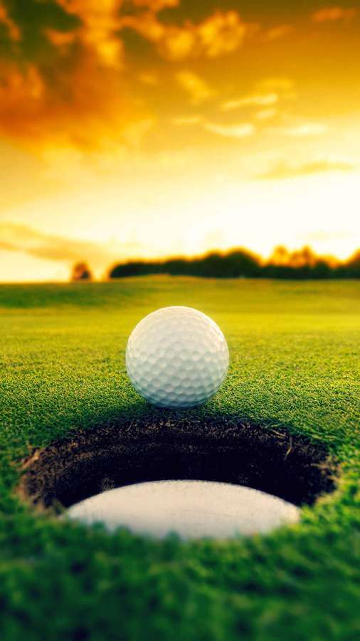 Golf ball on edge of hole on green grass at golden sunset. — Cool Golf Wallpaper