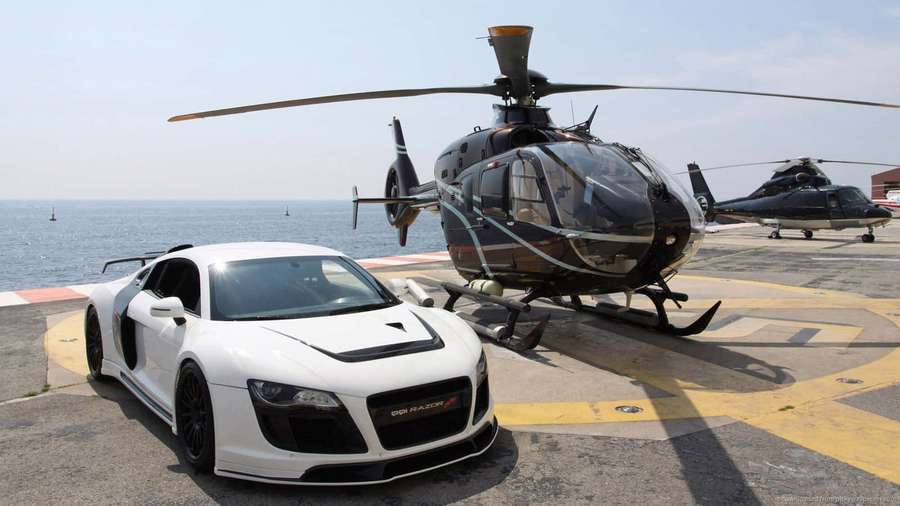 White sports car and black helicopter on helipad near ocean. — Cool Helicopter Background