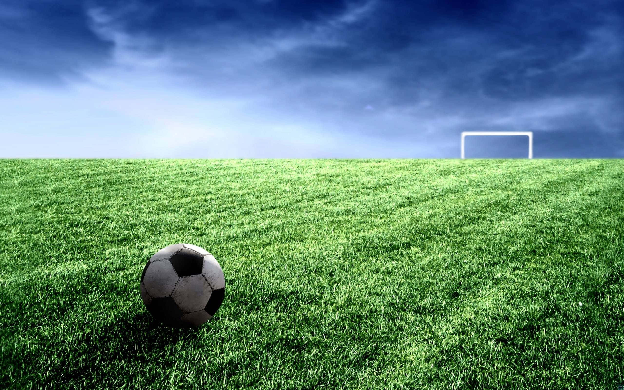 Fodbold på græsbane med mål i det fjerne under skyet himmel — Cool Soccer Wallpapers