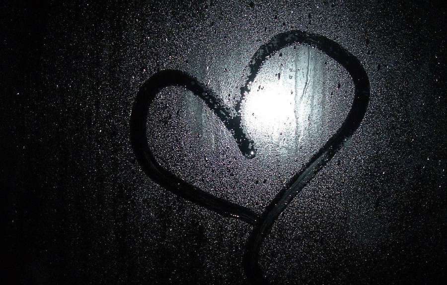Corazón dibujado en la lluvia sobre una ventana oscura con luz brillante que brilla a través. — Corazón Oscuro Fondos de pantalla