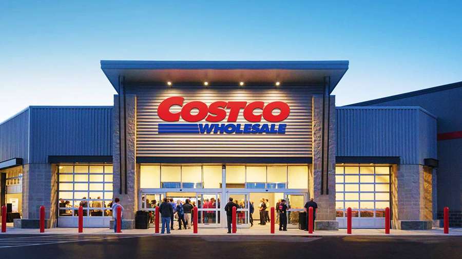 Eingang des Costco Wholesale Stores mit eintretenden Käufern in der Dämmerung. — Costco Hintergrundbild