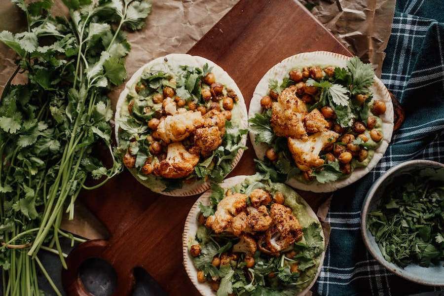 Três tacos de couve-flor e grão-de-bico assados com coentro em uma tábua de madeira. — Couve-flor Papéis de Parede