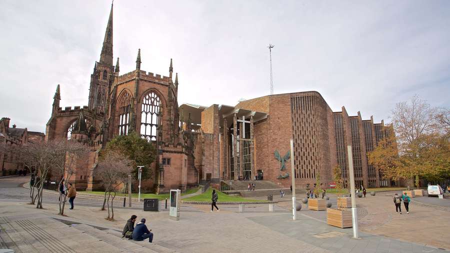 A historic cathedral next to a modern building with people in a public square. — Coventry Wallpaper