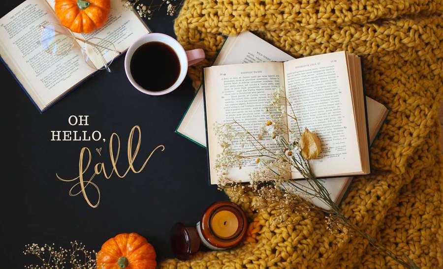 Fall-themed cozy setup with books pumpkin coffee and candle on dark surface. — Cozy Background
