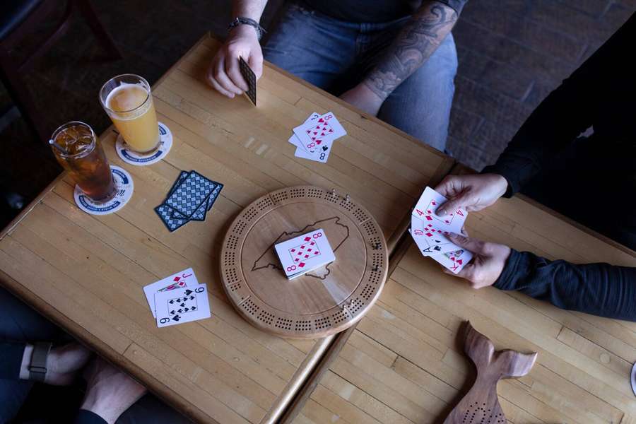 Personas jugando a las cartas y al cribbage en una mesa de madera con bebidas. — Cribbage Fondos de pantalla