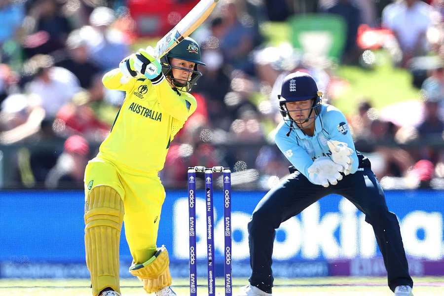 Cricket player in yellow batting with wicketkeeper in blue crouching behind stumps. — Cricket Picture
