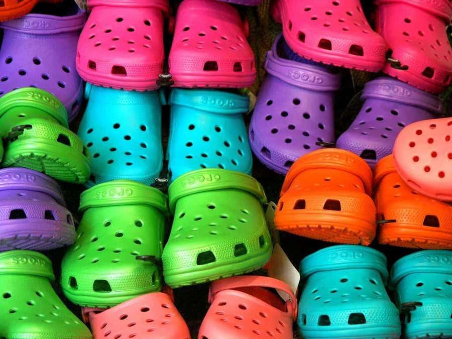 Stacks of colorful Crocs clogs in bright neon shades. — Crocs Background