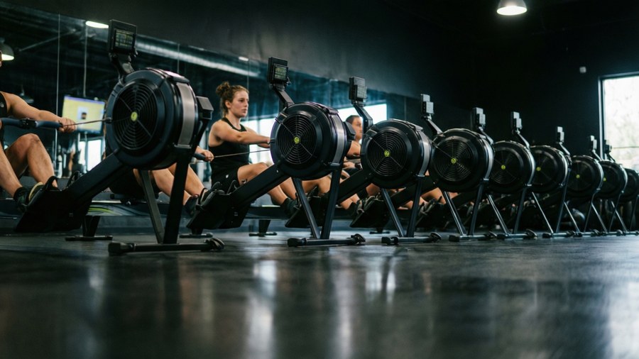 Low angle shot of rowing machines in a dark gym with glowing monitors. — Crossfit Wallpaper