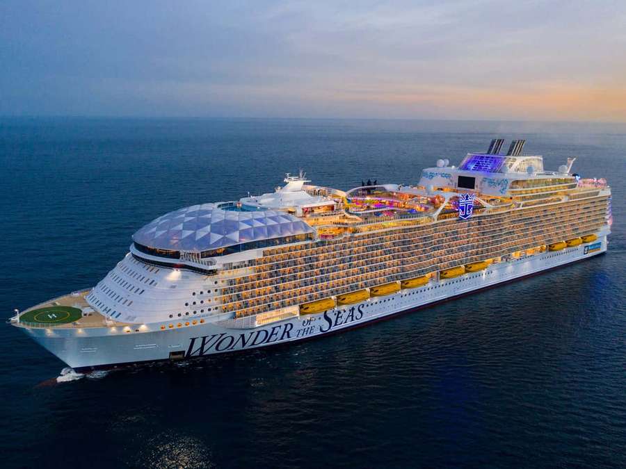 Wonder of the Seas cruise ship sailing at sunset with illuminated decks. — Cruise Picture