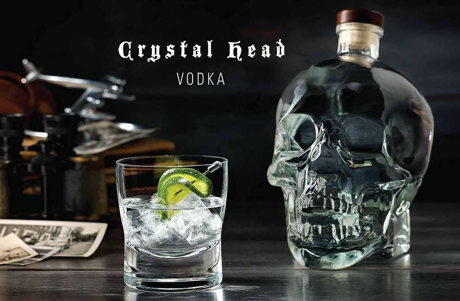 Skull-shaped vodka bottle and cocktail glass with ice and lime on a wooden table. — Crystal Head Vodka Wallpaper