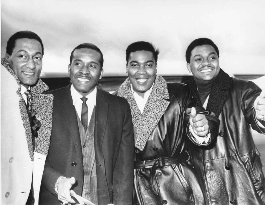 Cuatro hombres elegantes con abrigos sonriendo y posando al aire libre en blanco y negro. — Cuatro Tops Fondos de pantalla