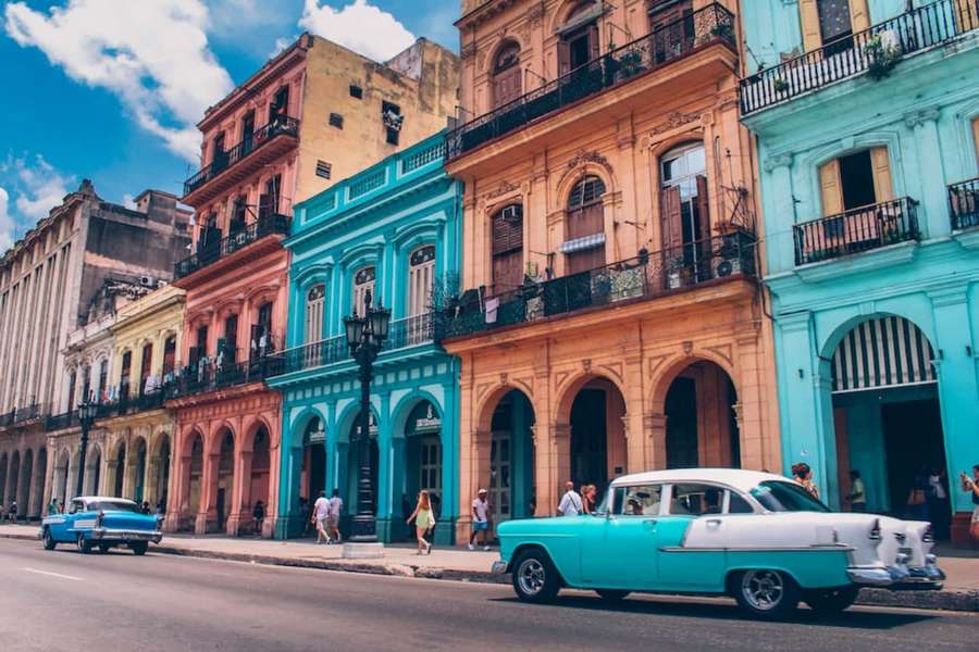 Colorful colonial buildings and vintage cars on a sunny Havana street with pedestrians. — Cuba Picture