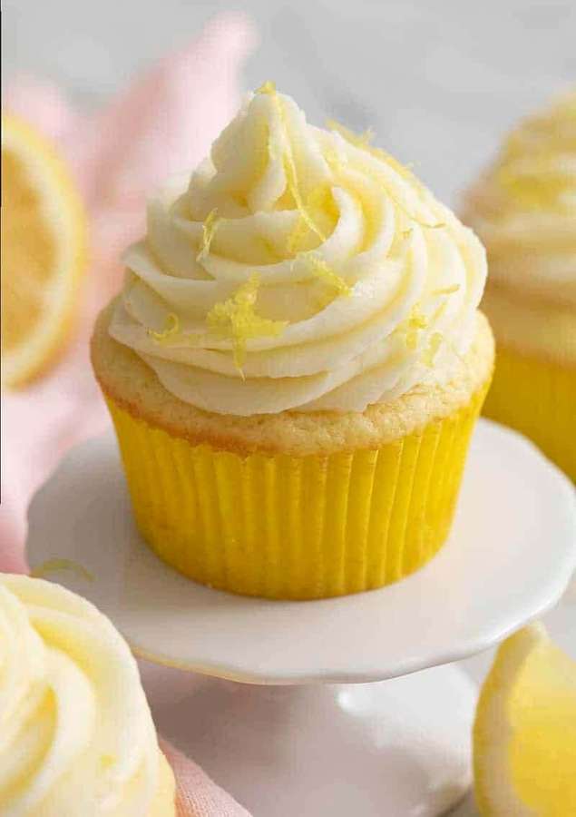 Zitronen-Cupcake mit Swirl-Frosting und Zesten-Garnitur auf einem weißen Ständer. — Cupcake Bilder