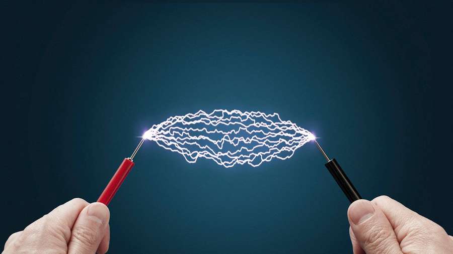 Hands holding probes creating an electric arc in a lab setting. — Current Wallpaper