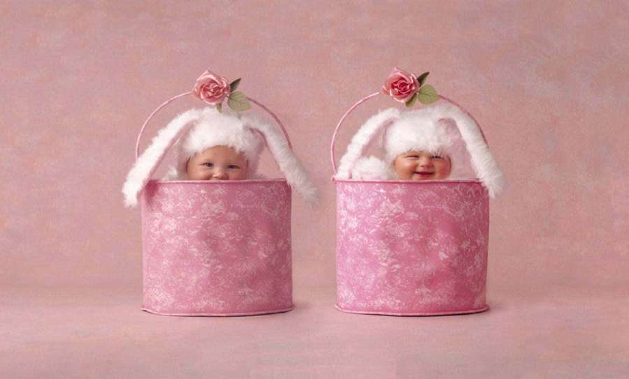 Two happy babies wearing bunny ears in pink buckets with floral patterns. — Cute Babies Wallpaper