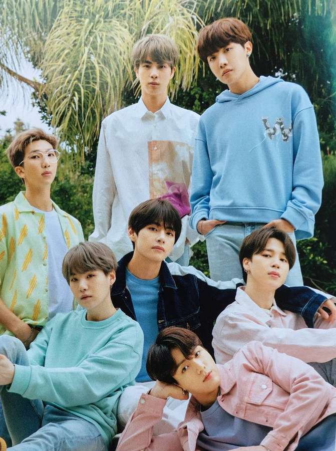 Seven stylish young men in pastel outfits posing outdoors among palm trees. — Cute Bts Background