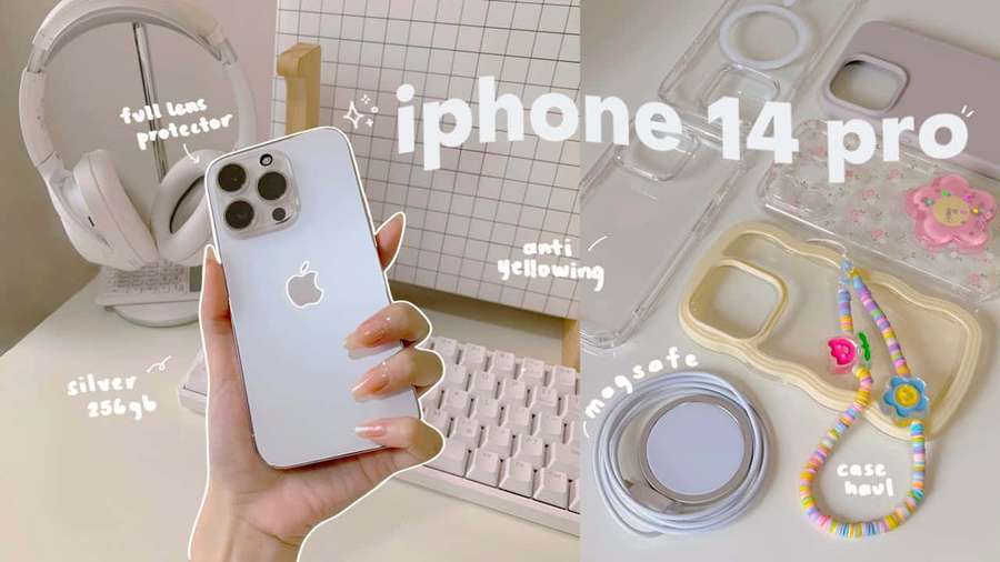 Hand holding silver iPhone 14 Pro with accessories on a pastel desk setup. — Cute iPhone Picture