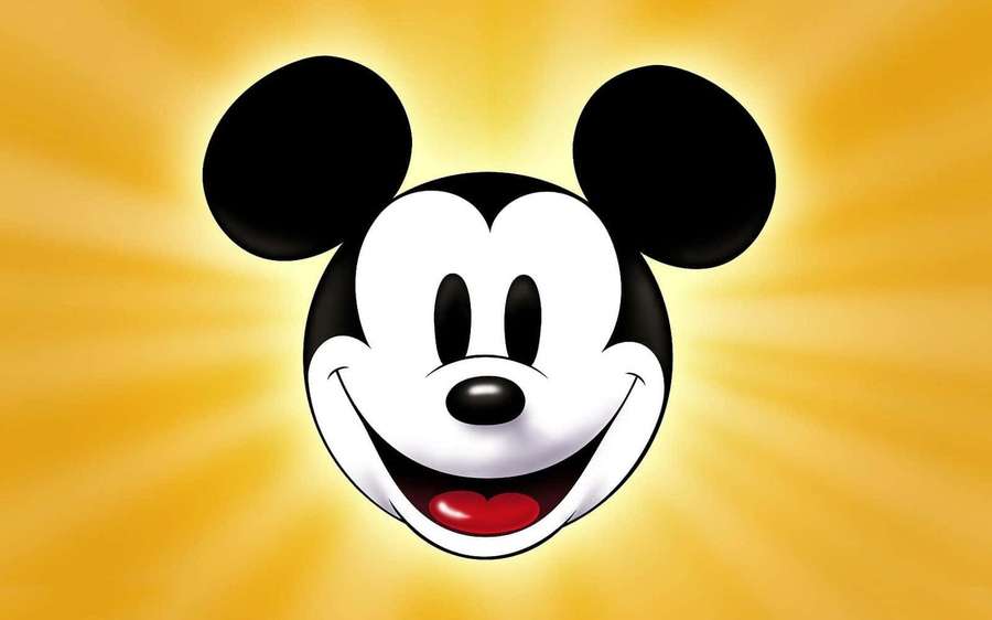 Mickey Mouse smiling with black ears against a golden sunburst background. — Cute Mickey Mouse Wallpaper