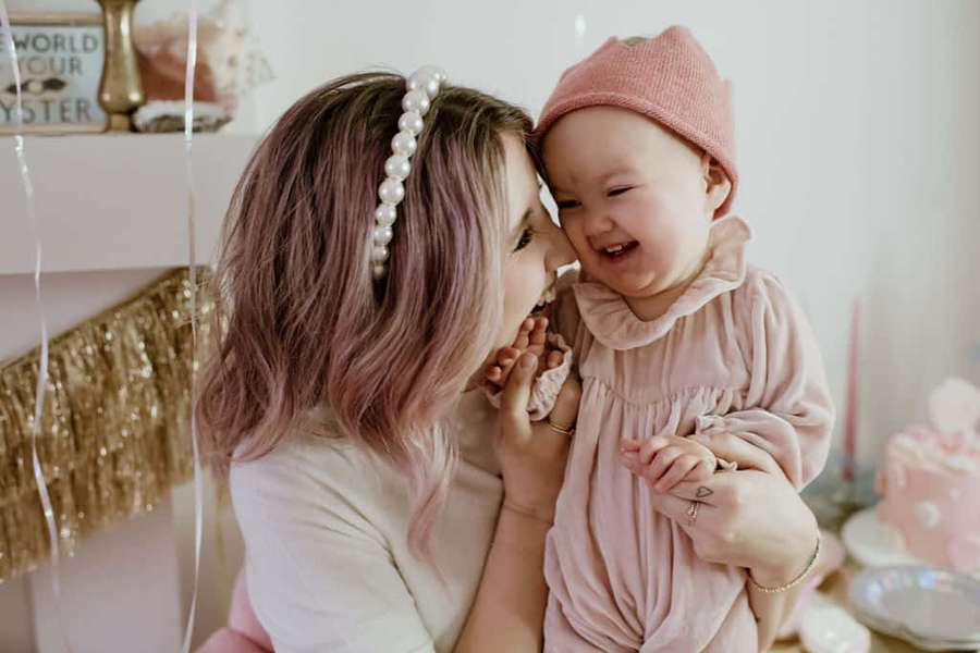 Mother and baby laughing together at a pink-themed celebration. — Cute Sister Wallpaper