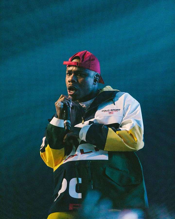 Rapper tritt auf der Bühne in bunter Jacke und roter Mütze unter blauen Lichtern auf. — Dababy Telefon Wallpaper