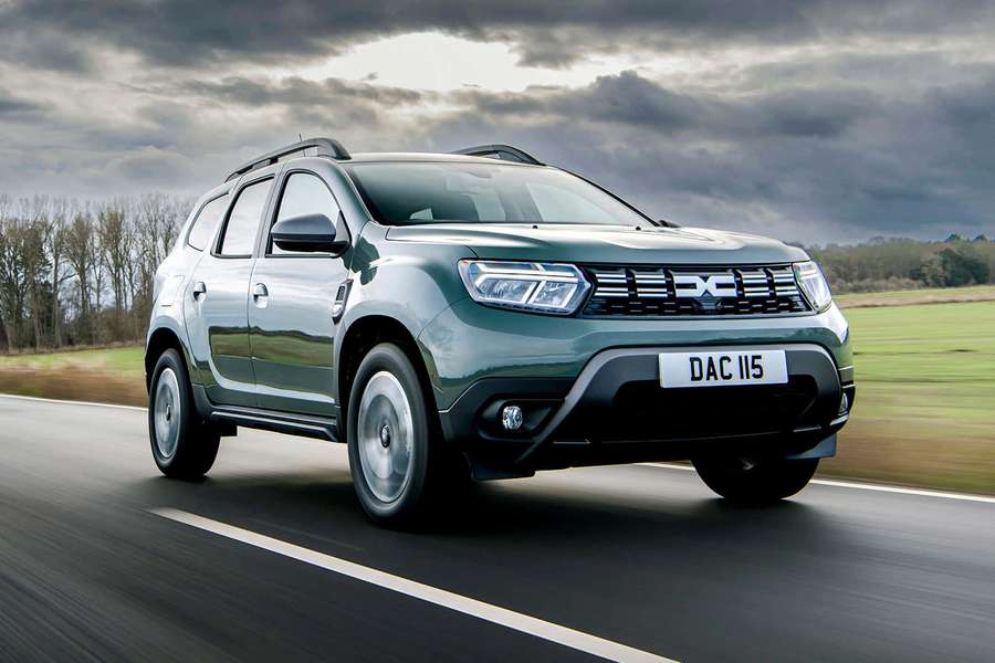 Grüner Dacia Duster SUV fährt auf einer Straße mit bewölktem Himmel und Grasfeldern — Dacia Duster Wallpaper