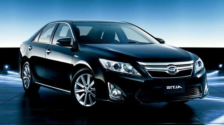 Black sedan with chrome accents under studio lighting on reflective floor. — Daihatsu Wallpaper