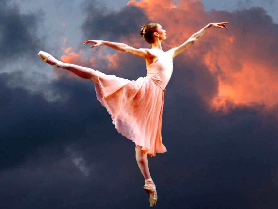 Ballerina in pink tutu leaping against fiery sunset clouds. — Dancer Picture
