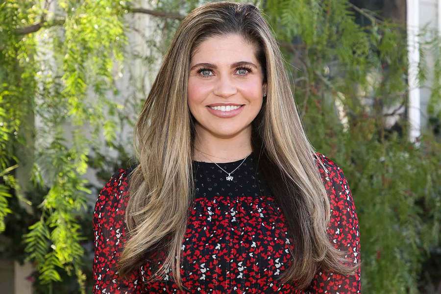 Woman in red floral dress smiling outdoors with green foliage behind her. — Danielle Fishel Wallpaper