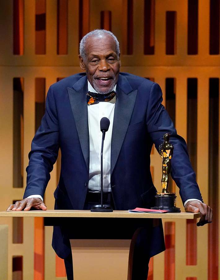 Danny Glover smiles while holding his Oscar award on stage. — Danny Glover Wallpaper