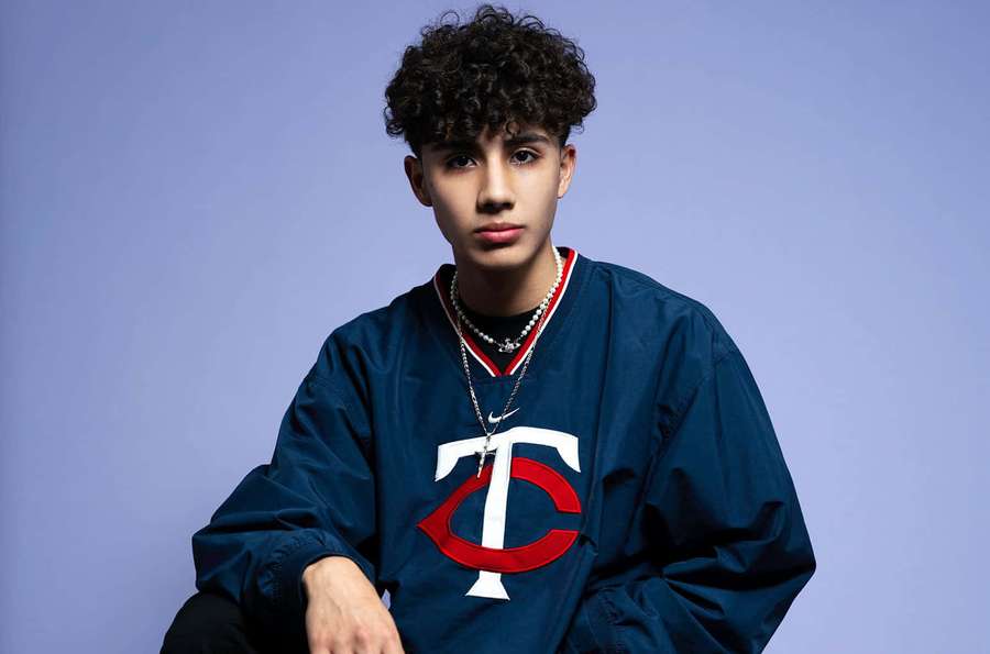 Young man in Minnesota Twins jacket posing in studio with purple background. — Danny Lux Wallpaper