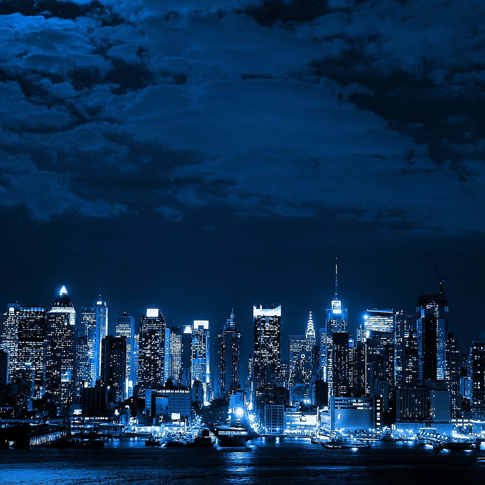 Pemandangan langit kota bernuansa biru di malam hari dengan bangunan bercahaya dan pantulan air. — Dark Blue Aesthetic Wallpaper