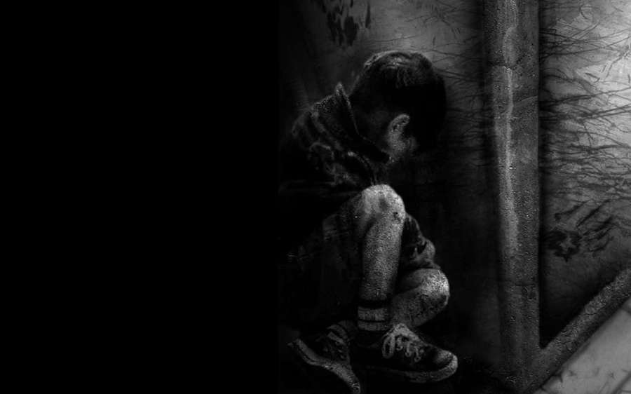 Child curled in dark corner of dilapidated room looking down — Dark Depressing Wallpaper