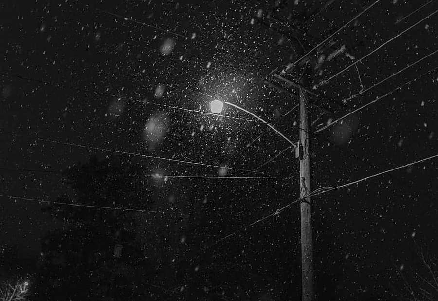 Snø faller rundt en gatelykt om natten med kraftledninger over. — Dark Winter Aesthetic Bakgrunner