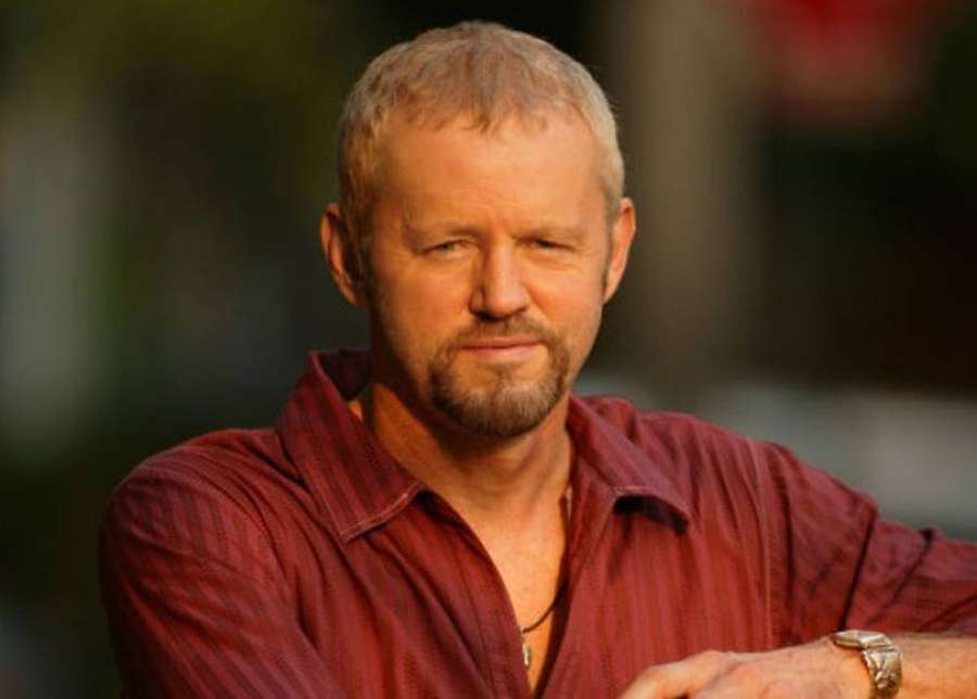 A man with a beard wearing a red shirt and watch looks calmly at the camera. — David Morse Wallpaper