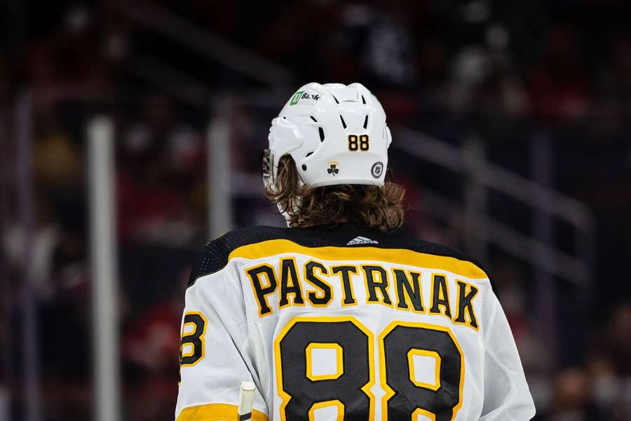 Hockey player Pastrnak in white jersey number 88 on ice rink — David pastrnak Background